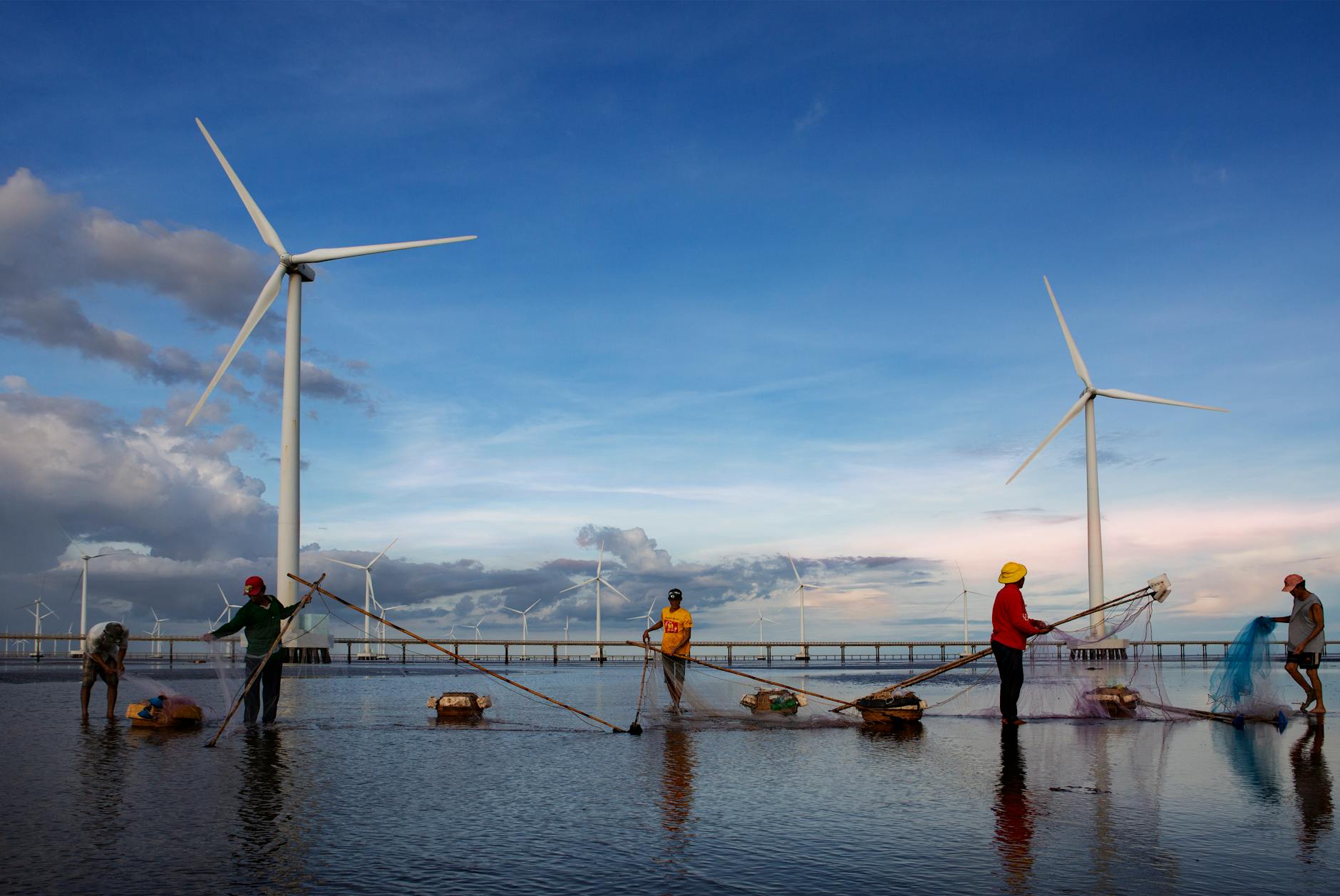 photo of fishermen working near wind turbines